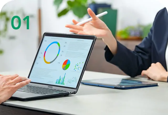 ノートパソコンの画面に表示された円グラフや棒グラフを元に、ビジネスミーティングをしている様子